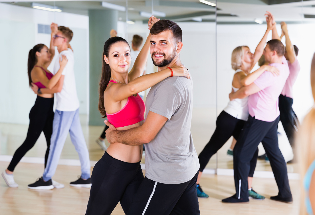 Dancing couples learning salsa at dance class